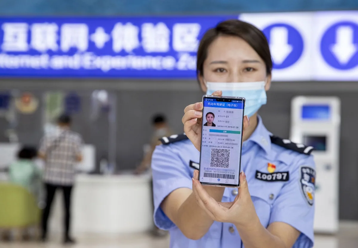 A traffic officer showing a digital Chinese driving licence on a phone
