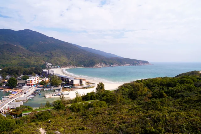 La playa de Dongchong, su orilla curva de arena y barcos cercanos al pie de colinas verdes