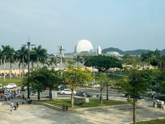 El teatro de la ópera de Zhuhai, con forma de conchas, tras las palmeras y Lovers Road, visto desde el Museo de Zhuhai
