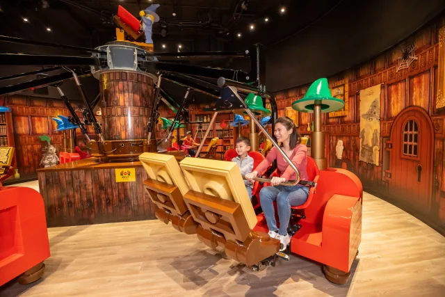 Una adulta y un niño en la atracción Merlin’s Apprentice del centro de Hong Kong