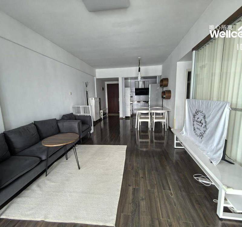 Living room with dark wooden flooring, a dark sofa and a dining area in the Peninsula Phase I advertiser's gallery
